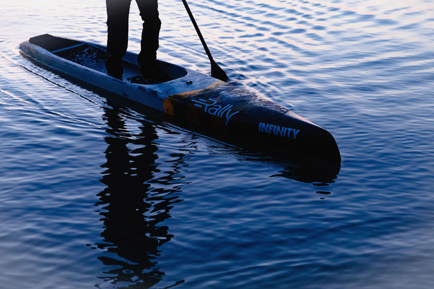 person stand up paddle boarding on a Rally Beer paddle board